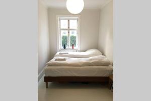 1 dormitorio con 2 camas y ventana en Central Apartment in attractive Østerbro en Copenhague