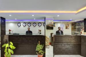 two men sitting at a counter with clocks on the wall at Hotel Windsor Castle Inn Brigade Rd in Bangalore