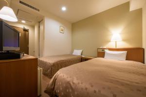 a hotel room with two beds and a flat screen tv at Pacific Hotel Shiroishi in Shiroishi