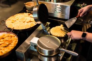 a person cooking food on a grill with pies at Aurico Kata Resort & Spa - SHA Extra Plus in Kata Beach