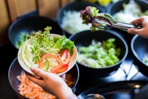 a person holding a bowl of food on a table at Aurico Kata Resort & Spa - SHA Extra Plus in Kata Beach