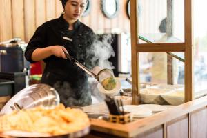 a person is cooking food in a kitchen at Aurico Kata Resort & Spa - SHA Extra Plus in Kata Beach
