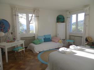 um quarto com 2 camas, uma mesa e janelas em La Clorinde em Moustiers-Sainte-Marie