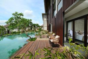 uma piscina de resort com cadeiras e uma cama num deque em The Garcia Ubud Hotel & Resort em Ubud