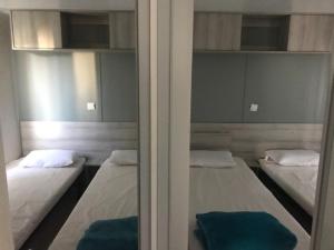 2 camas en una habitación con espejo en Mobile Home For You Quiberon en Quiberon