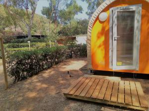 an orange and yellow trailer with a wooden deck at Elbadoc Camping Village in Cavo