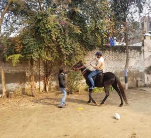 een man op een paard naast een jongen bij Nature Resort in Agra