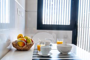una mesa con una cesta de fruta y vasos de zumo de naranja en Stay In Brisas del Sur, en Alicante