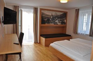 a bedroom with a bed and a desk and a television at Hotel Gasthof Tirolerwirt in Bischofshofen