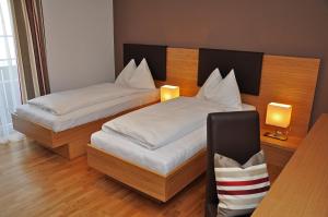 sypialnia z 2 łóżkami i 2 lampkami na ścianie w obiekcie Hotel Gasthof Tirolerwirt w mieście Bischofshofen