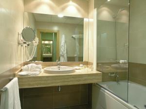 uma casa de banho com um lavatório, um chuveiro e um espelho. em Blu Hotel Pamplona em Imárcoain