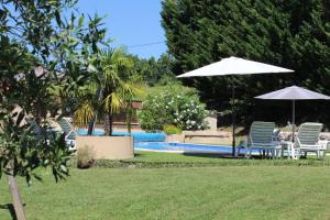 a group of chairs and umbrellas next to a pool at Logis des Crêtes de Pignols in Moissac