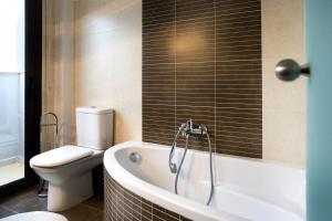 a bathroom with a bath tub and a toilet at Melon Suites in Thessaloniki