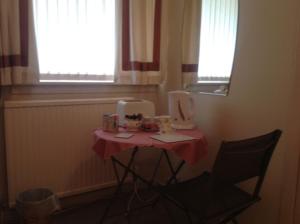 una mesa en una habitación con una mesa con una silla y dos ventanas en The Clan Boyd Room en Kilmarnock