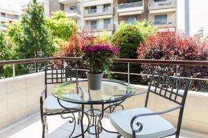 a glass table and chairs on a balcony with flowers at Melon Suites in Thessaloniki