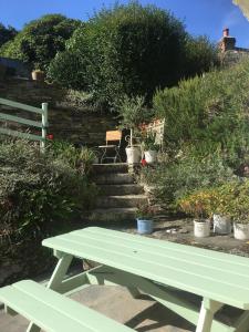 特魯羅的住宿－The Thatched Cottage，花园里的绿色野餐桌,种有盆栽植物