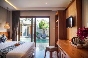 a bedroom with a bed and a tv and a pool at Bisma Terrace Suite Ubud in Ubud
