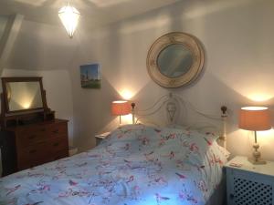 1 dormitorio con 1 cama, 2 lámparas y espejo en The Thatched Cottage, en Truro