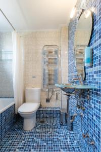 a blue tiled bathroom with a toilet and a sink at Melon Suites in Thessaloniki