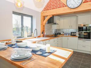 a kitchen with a wooden table with a clock on the wall at 1 Stud Cottage in Norwich