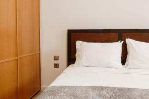 a bedroom with a bed with white sheets and pillows at Melon Suites in Thessaloniki
