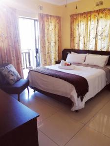 een slaapkamer met een groot bed en een stoel bij Hilton Gardens Guesthouse in Richards Bay