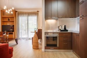 a kitchen with wooden cabinets and a living room at Melon Suites in Thessaloniki
