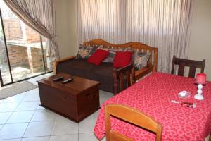 a bedroom with a bed and a table with a red table cloth at ASAMé @ Oppi-Rivier in Christiana