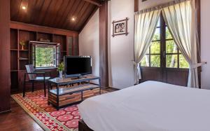 a bedroom with a bed and a tv and a window at Sanctuary Hotel Luang Prabang in Luang Prabang
