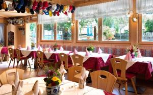 un comedor con mesas, sillas y ventanas en Gasthof zum Schlern, en Fiè