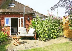 a garden with a chair in front of a house at Hollyhocks in Bawdsey