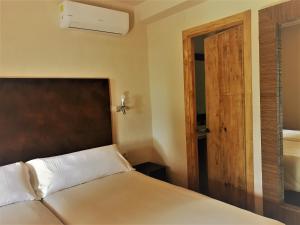 1 dormitorio con 1 cama y puerta de madera en Chillout Hotel Tres Mares en Tarifa