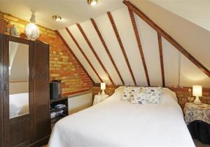 a bedroom with a white bed and a staircase at Hollyhocks in Bawdsey