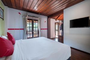 a bedroom with a white bed and a flat screen tv at Sanctuary Hotel Luang Prabang in Luang Prabang