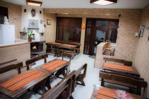 a restaurant with wooden tables and benches and a stove at Станчевата Къща in Zlatograd