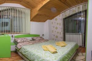 a bedroom with a green bed with yellow pillows on it at Stanchevata Kashta in Zlatograd