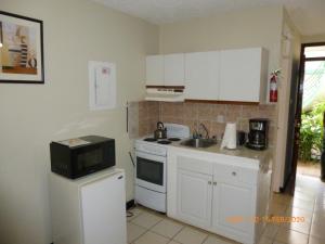 a kitchen with white cabinets and a sink and a microwave at SandCastles Holiday #C9 in Ocho Rios