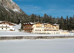 a large building in the snow in front of a mountain at Hotel Kirchdach in Gschnitz
