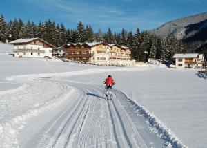 a person on skis in the snow in front of a lodge at Hotel Kirchdach in Gschnitz
