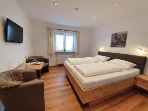 1 dormitorio con cama, sofá y TV en Landhaus Ruppaner, en Fischen