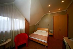 a small bedroom with a bed and a red chair at Belogorye Hotel in Belgorod