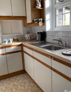 una cocina con armarios blancos y fregadero en Tolpuddle Hideaway, Tolpuddle, Dorset en Dorchester