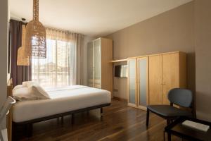 um quarto com uma cama, uma cadeira e uma janela em Barcelona Apartment Aramunt em Barcelona