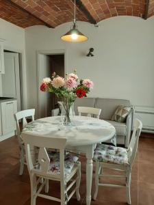 una mesa de comedor blanca con un jarrón de flores. en Il Cuoricino Podere le Bozze con piscina, WI-FI, posto auto, en Castagneto Carducci