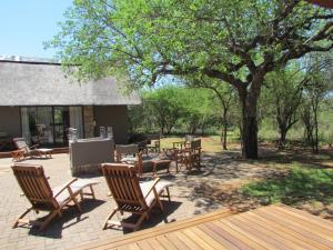 a patio with chairs and tables under a tree at Swiblati Lodge in Hoedspruit