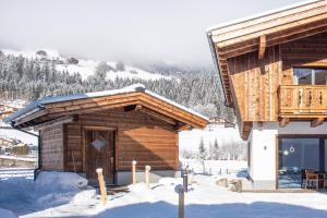 a log cabin in the snow with a balcony at Chalet's DAS DORF in Wald im Pinzgau