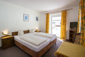a hotel room with two beds and a television at Gasthof Alpenrose und Pension Nina in Gschnitz