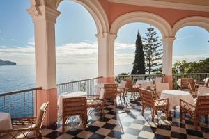 a restaurant with tables and chairs on a balcony at Reid's Palace, A Belmond Hotel, Madeira in Funchal
