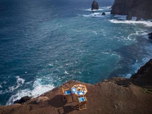 two beach chairs sitting on a cliff near the ocean at Reid's Palace, A Belmond Hotel, Madeira in Funchal