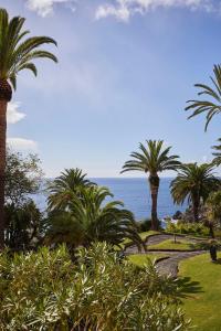 a view of the ocean from a park with palm trees at Reid's Palace, A Belmond Hotel, Madeira in Funchal